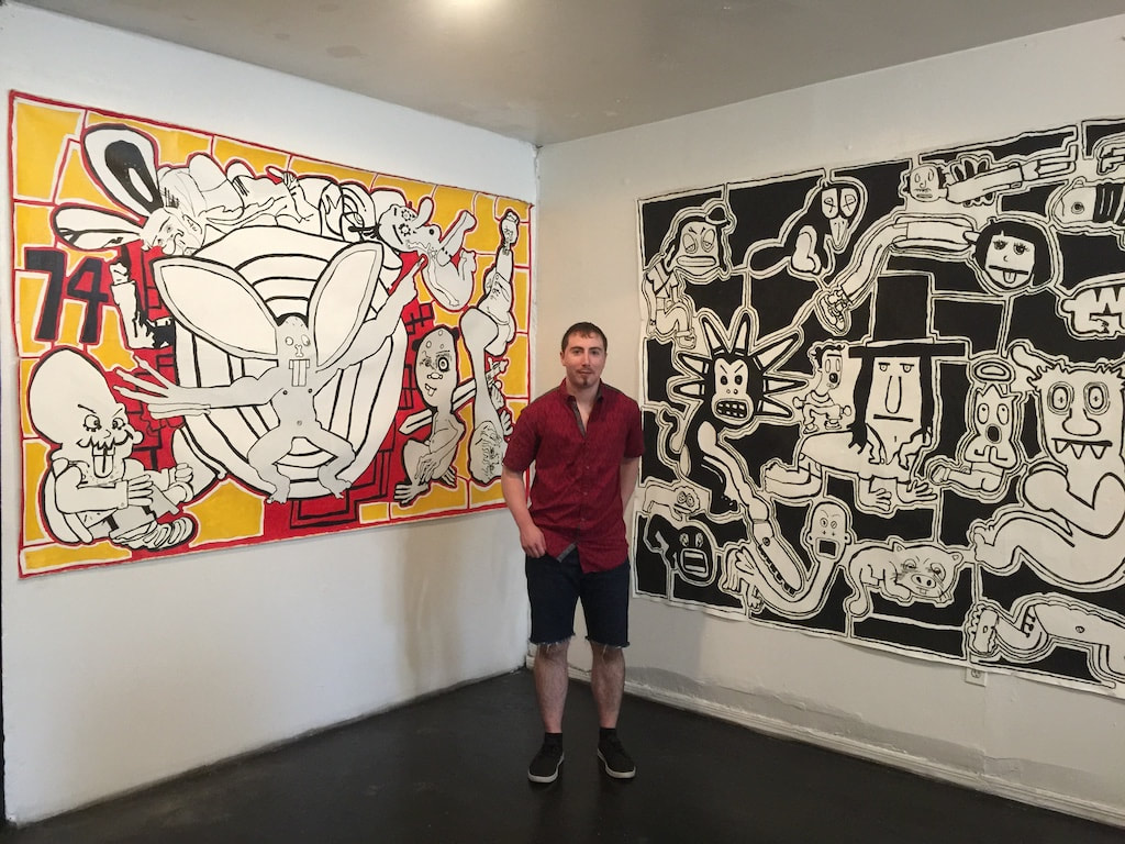 Artist Quinn Marston next to his large, contemporary acrylic paintings in a gallery exhibition 